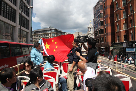 中國游客們在安凱雙層車上揚(yáng)起國旗為奧運(yùn)健兒助威