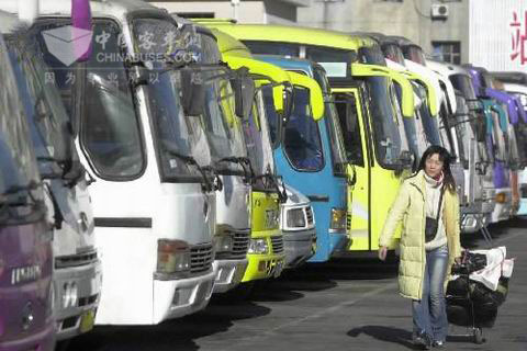 一位回家的旅客經(jīng)過?？吭谄囌纠镎b待發(fā)的大客車前